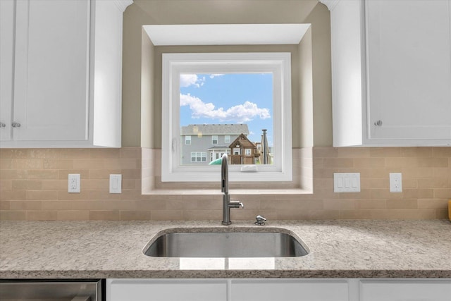kitchen with a sink, white cabinets, and backsplash