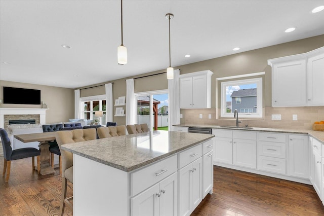 kitchen with a sink, backsplash, a kitchen island, and a wealth of natural light