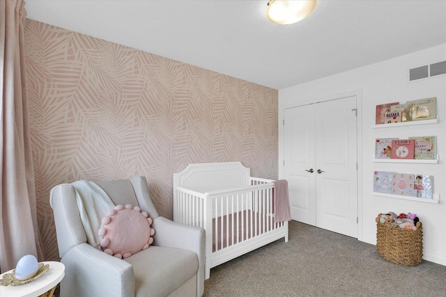 carpeted bedroom featuring a nursery area, wallpapered walls, baseboards, visible vents, and a closet