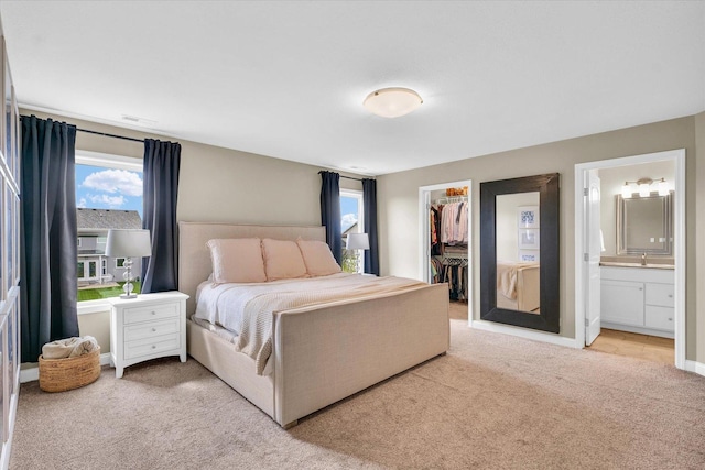 carpeted bedroom with a walk in closet, visible vents, a closet, and connected bathroom