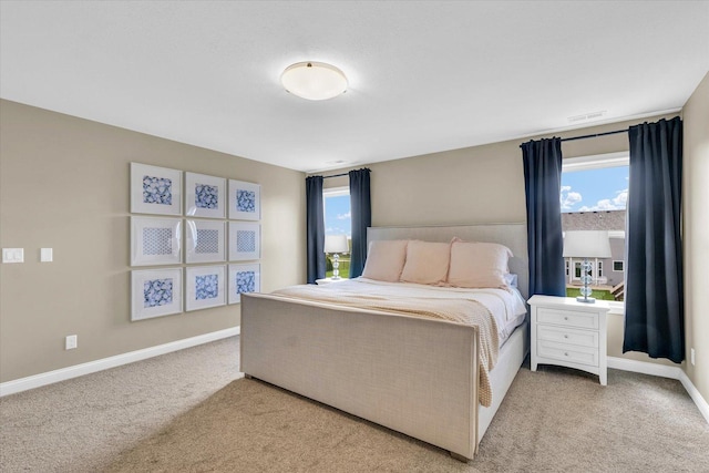 bedroom with baseboards, light colored carpet, and visible vents