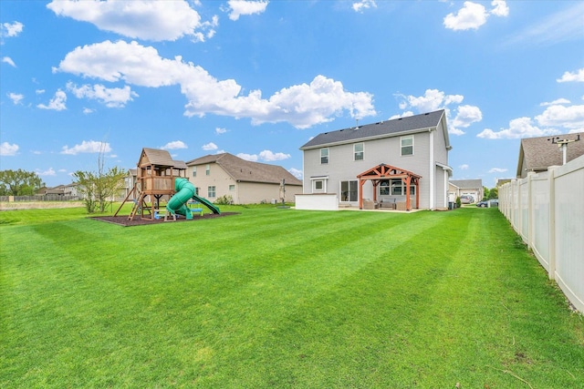 back of house with a playground, fence, a gazebo, and a lawn