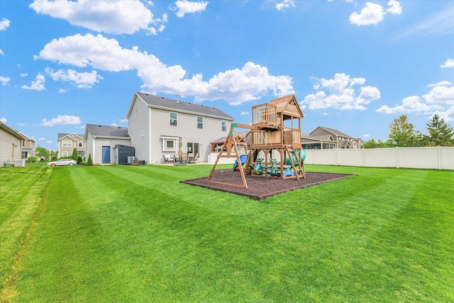 back of property with a playground, fence, and a lawn