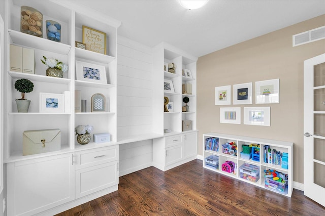 interior space with dark wood finished floors, built in desk, and visible vents