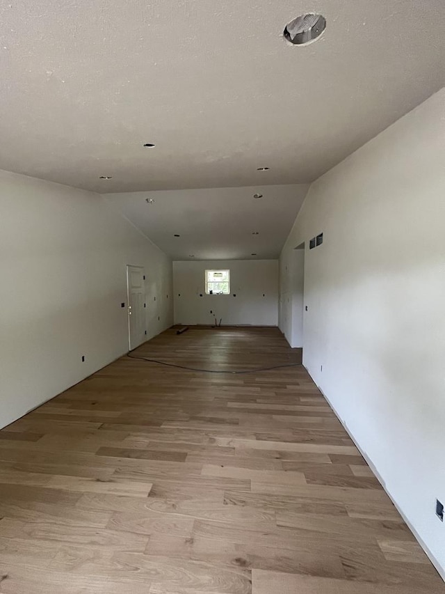 unfurnished room featuring vaulted ceiling and light wood-type flooring