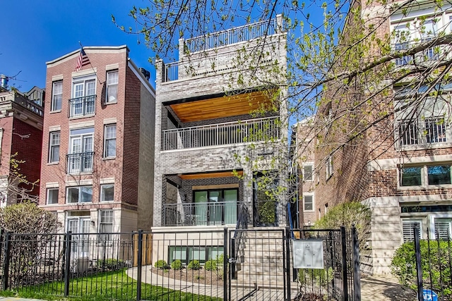view of front of house with brick siding, a fenced front yard, and a balcony