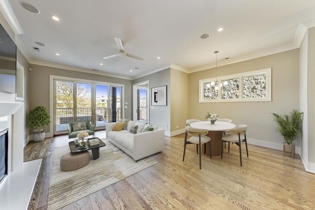 living area featuring baseboards, ornamental molding, ceiling fan with notable chandelier, and light wood finished floors