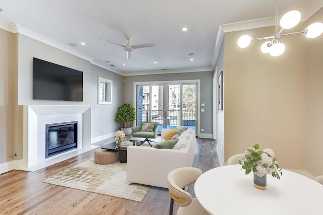 living room with a fireplace with flush hearth, baseboards, ornamental molding, and wood finished floors