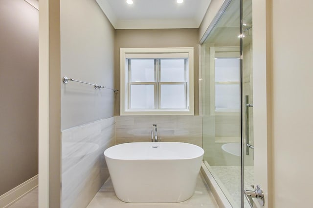 bathroom featuring recessed lighting, walk in shower, a freestanding bath, and tile walls