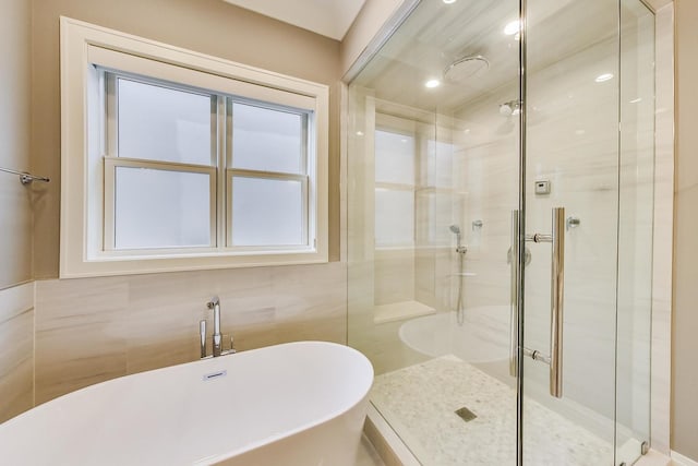 full bathroom featuring a soaking tub, tile walls, and a shower stall