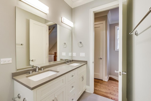 bathroom with a sink, baseboards, double vanity, and wood finished floors