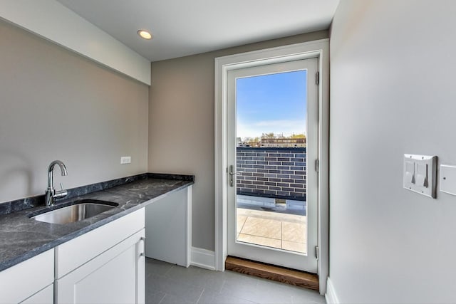 doorway with baseboards, dark tile patterned floors, recessed lighting, a sink, and wet bar