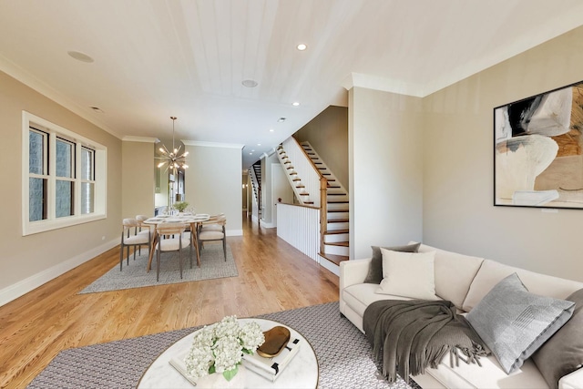 living area with crown molding, wood finished floors, baseboards, a chandelier, and stairs