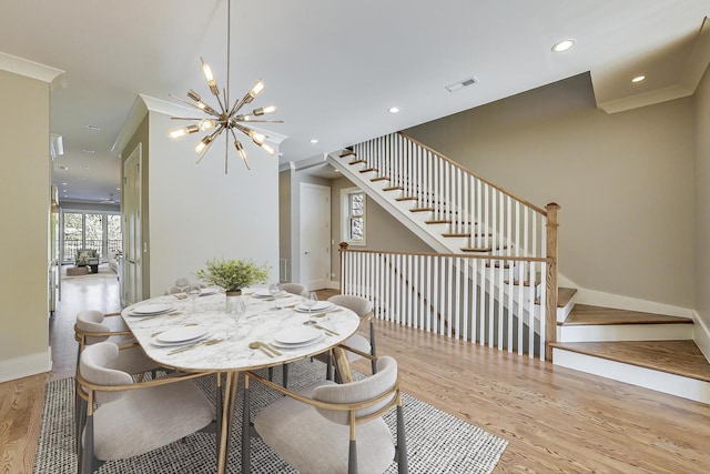 dining space with visible vents, an inviting chandelier, wood finished floors, baseboards, and stairway