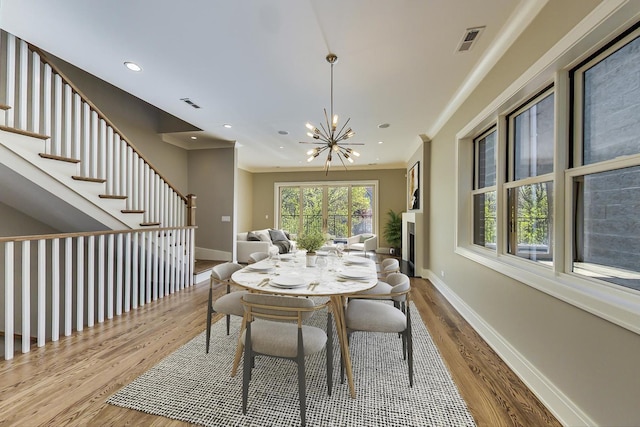 dining area featuring baseboards, a notable chandelier, visible vents, and wood finished floors