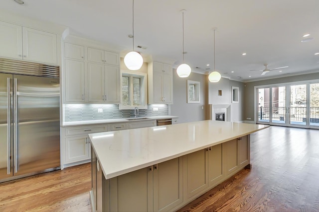 kitchen featuring a center island, a sink, light wood finished floors, appliances with stainless steel finishes, and backsplash