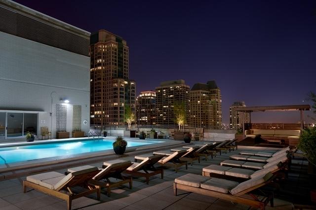 pool at twilight featuring a view of city lights and a community pool