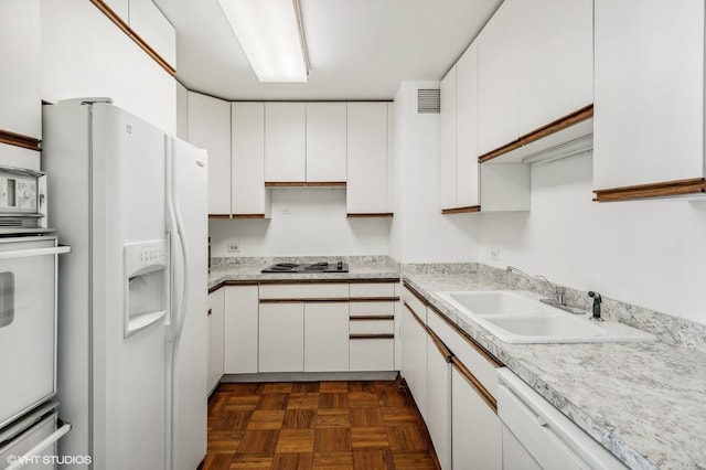 kitchen with light countertops, white cabinetry, a sink, and white appliances