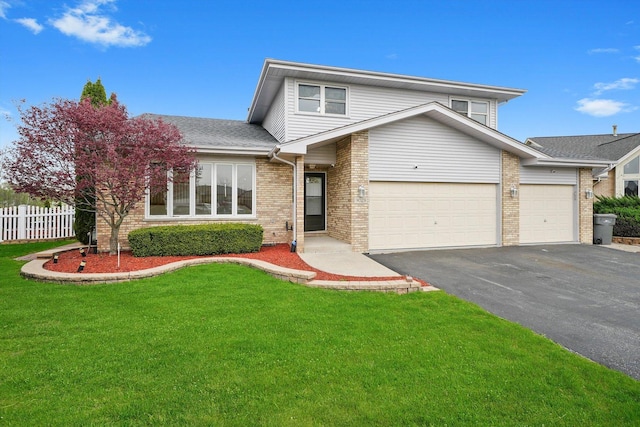 traditional home featuring fence, driveway, a front lawn, and brick siding