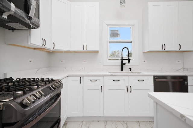 kitchen featuring appliances with stainless steel finishes, light stone counters, a sink, marble finish floor, and white cabinetry