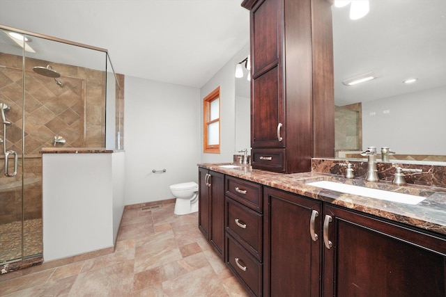 full bath with a sink, a shower stall, toilet, and double vanity