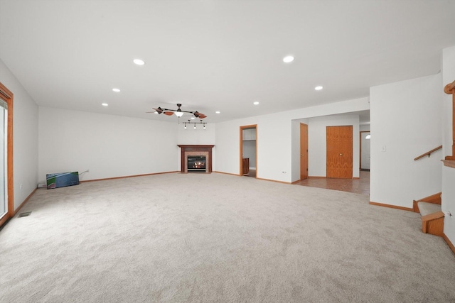 unfurnished living room featuring ceiling fan, light colored carpet, a tile fireplace, baseboards, and recessed lighting