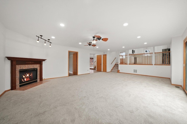 unfurnished living room featuring visible vents, baseboards, ceiling fan, a tiled fireplace, and carpet flooring