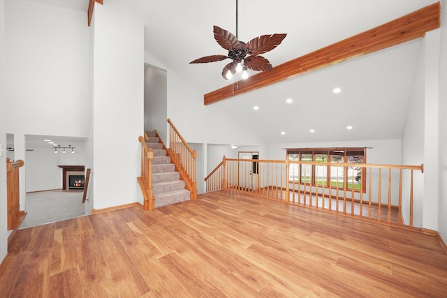 unfurnished living room featuring a lit fireplace, a ceiling fan, wood finished floors, high vaulted ceiling, and recessed lighting