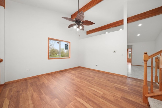 spare room featuring light wood finished floors, a ceiling fan, recessed lighting, beamed ceiling, and stairway