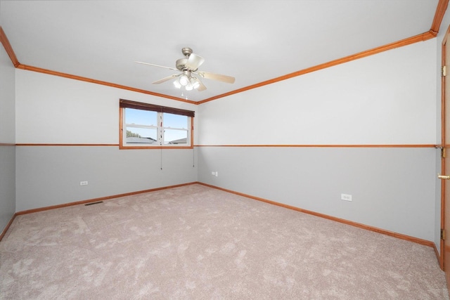 carpeted empty room with crown molding, baseboards, a ceiling fan, and visible vents