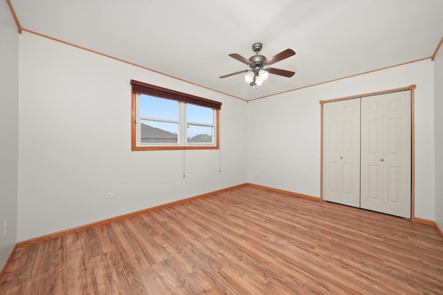 unfurnished bedroom featuring baseboards, ornamental molding, a ceiling fan, and light wood finished floors