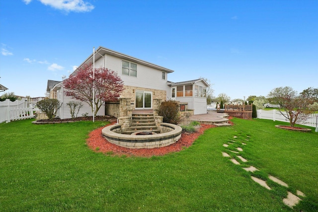 rear view of property featuring fence, a lawn, and stone siding