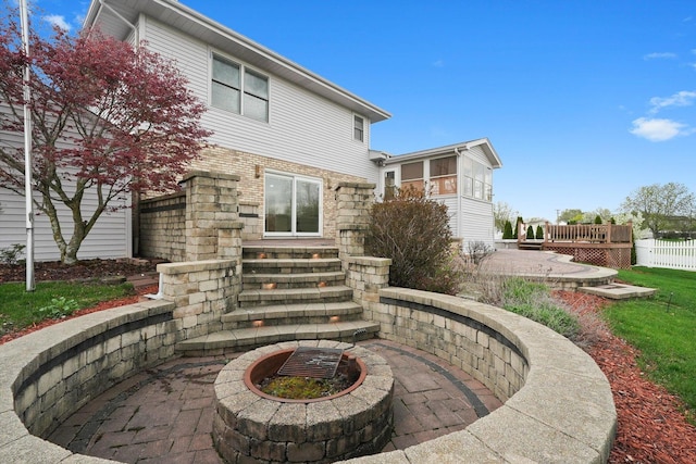 back of property with stone siding, fence, and entry steps