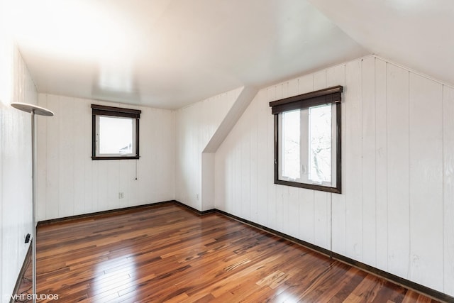 bonus room featuring hardwood / wood-style floors, wood walls, and lofted ceiling