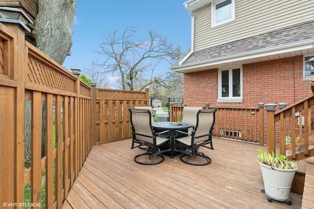wooden deck featuring outdoor dining area and a gate