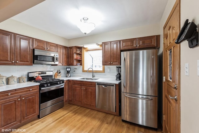 kitchen featuring a sink, stainless steel appliances, open shelves, light wood-style flooring, and backsplash