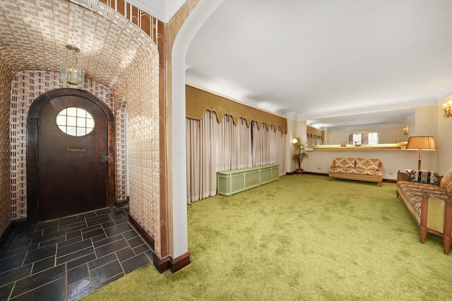 foyer entrance featuring carpet floors, arched walkways, and baseboards