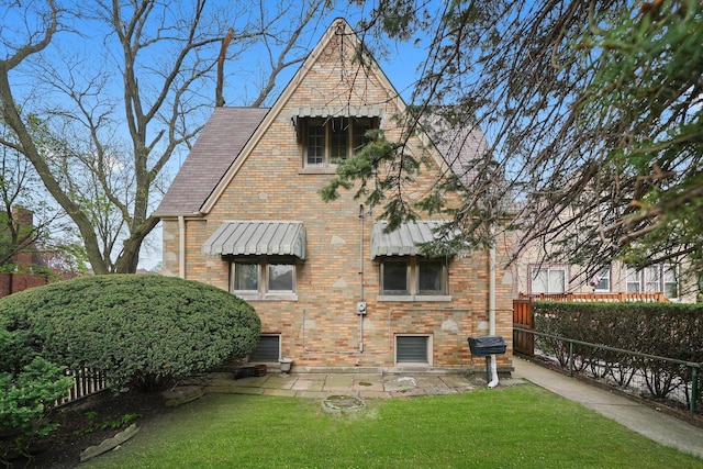 back of property with a lawn, brick siding, and fence