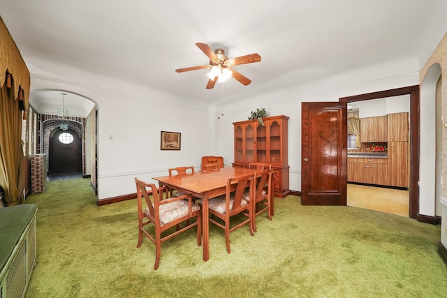 dining area with light colored carpet, arched walkways, baseboards, and ceiling fan