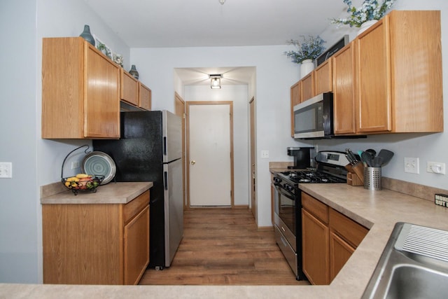 kitchen featuring dark wood-style floors, a sink, stainless steel appliances, and light countertops