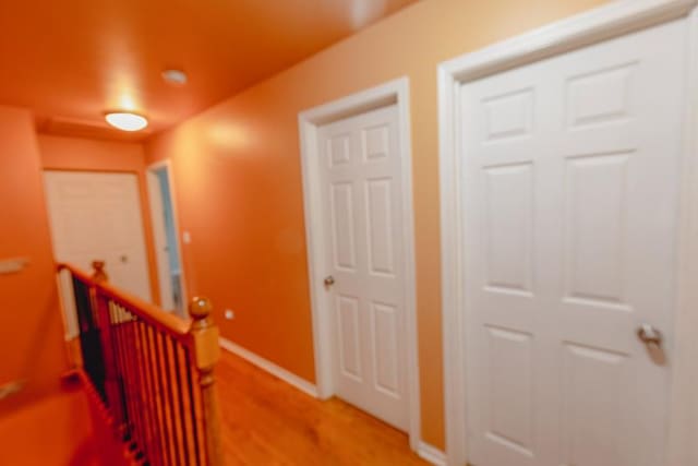 hallway with an upstairs landing, light wood-style flooring, and baseboards