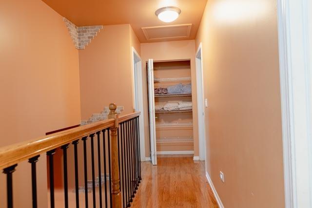 hall with an upstairs landing, light wood finished floors, and baseboards