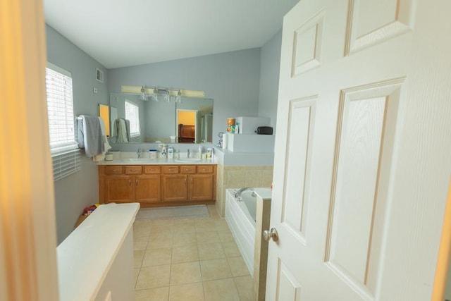 bathroom with lofted ceiling, tile patterned floors, a bath, and double vanity
