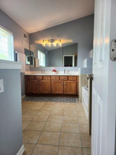 bathroom with tile patterned floors, plenty of natural light, double vanity, and a bath