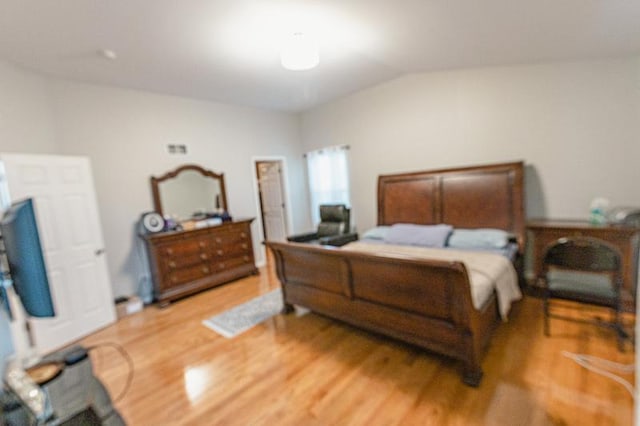 bedroom with light wood finished floors and vaulted ceiling