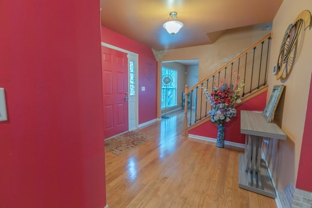 foyer entrance with light wood finished floors, baseboards, and stairs