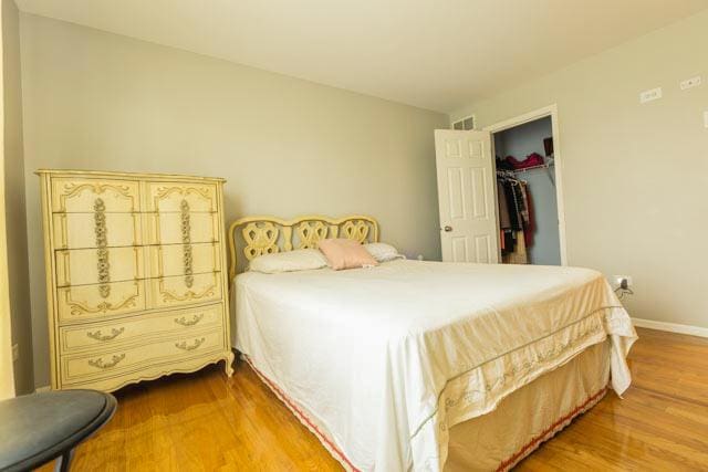 bedroom with wood finished floors, baseboards, a walk in closet, and a closet
