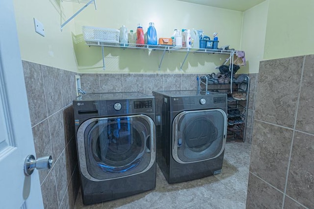 laundry room with tile walls, independent washer and dryer, and wainscoting