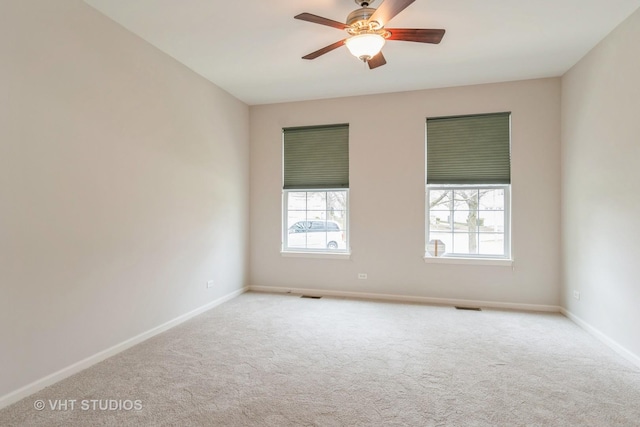 carpeted spare room with baseboards, visible vents, and ceiling fan