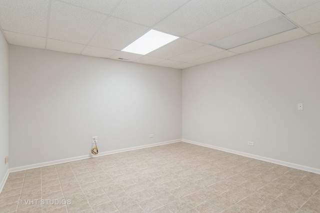 spare room with a paneled ceiling and baseboards